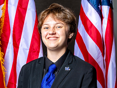  Student smiling in front of USA flags